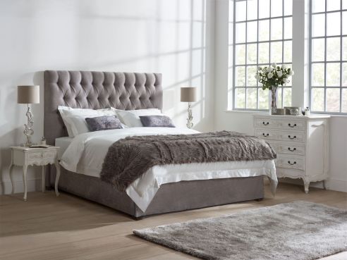 Lloyd bed shown in a stone colour harbour grey fabric, with a deep buttoned upholstered headboard.